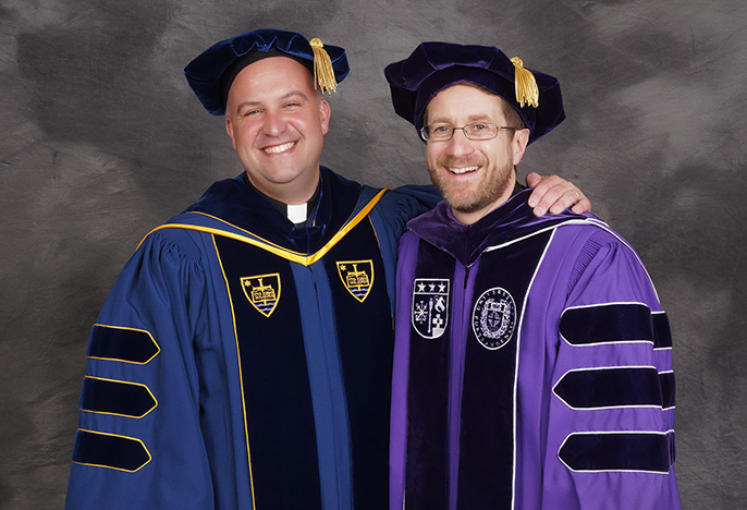 two priests dressed in medieval commencement outfits